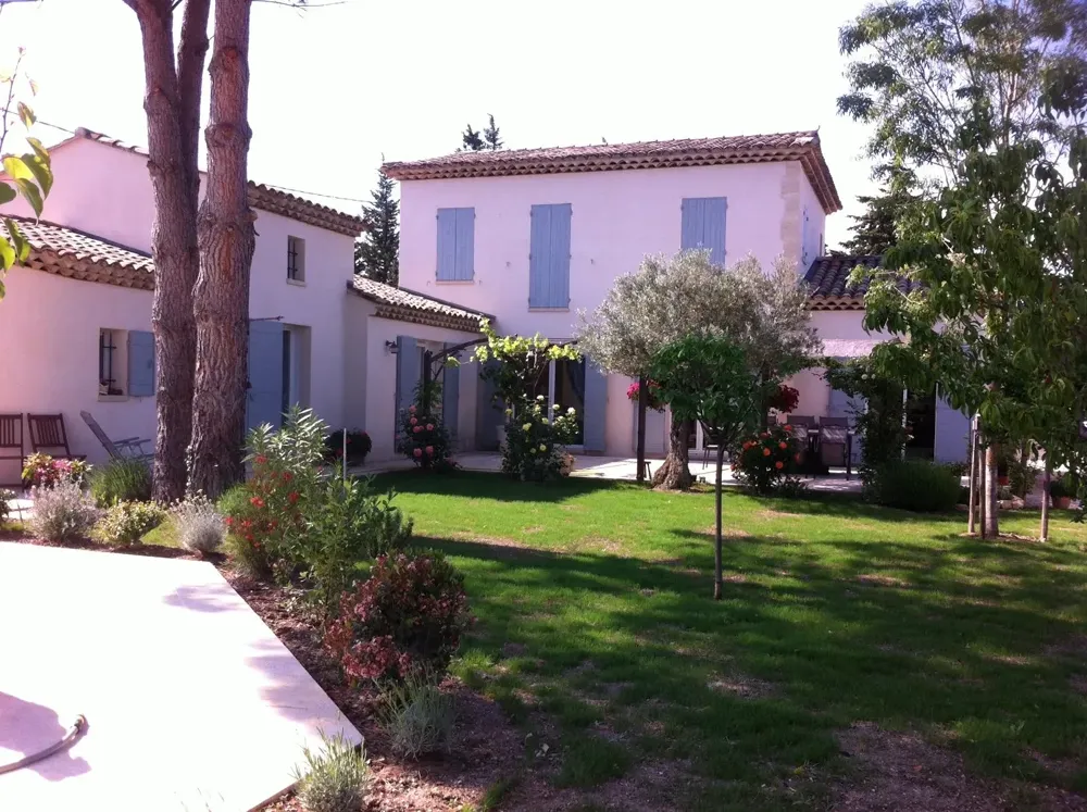 Maison provençale aux façades claires et volets bleus, olivier et pelouse devant la terrasse