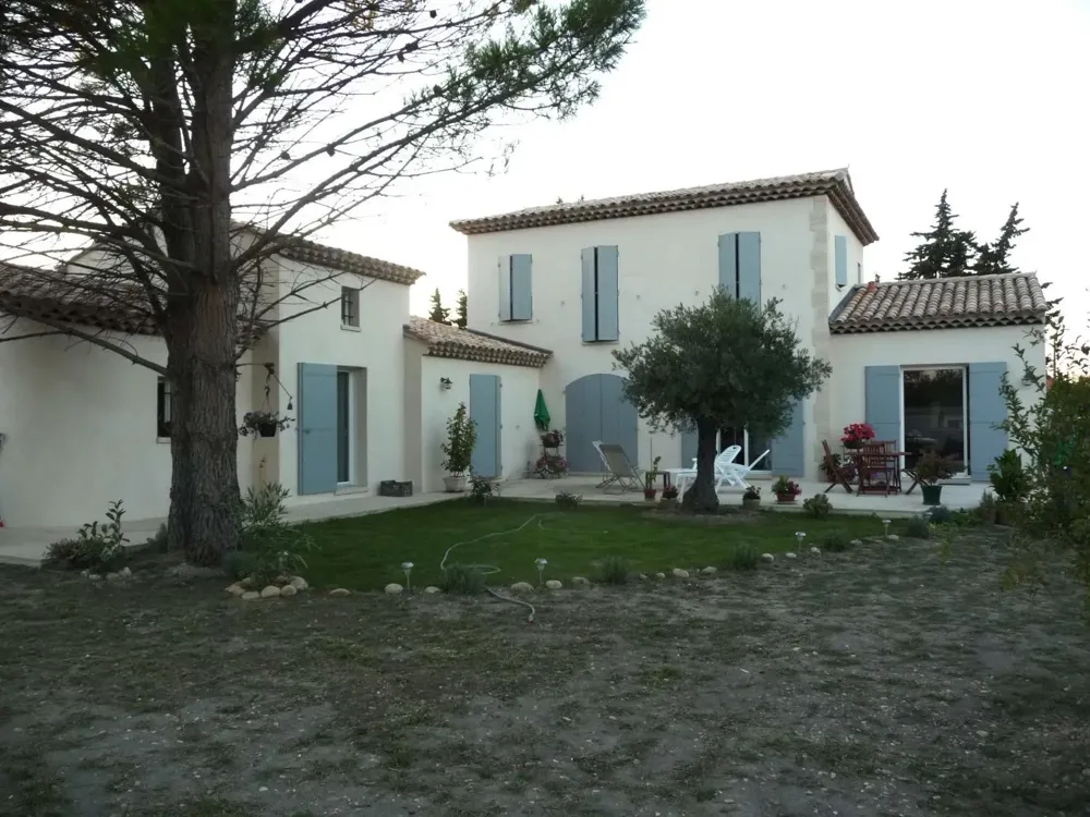 Maison provençale à étage aux volets gris-bleu, olivier et pelouse devant la terrasse, en fin de journée